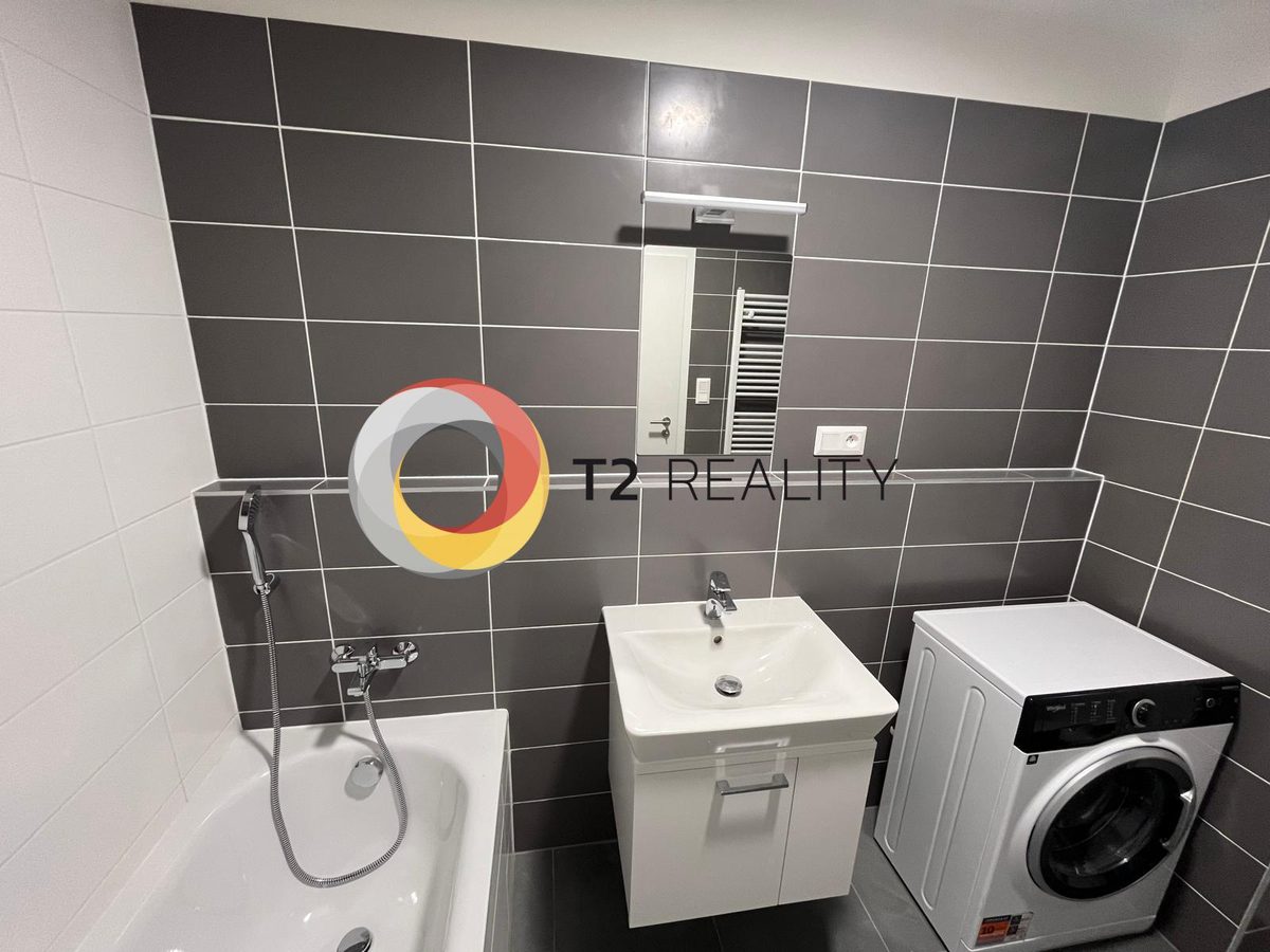 חדר אמבטיה מרוצף אפור כהה עם אמבט, ארון כיור ומכונת כביסה